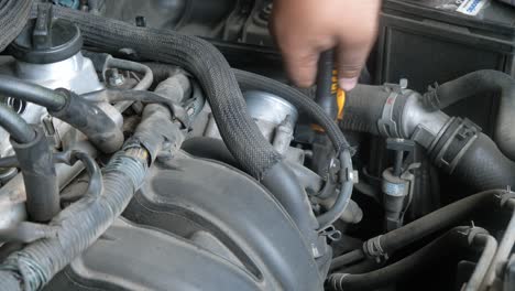 A-hand-with-a-pair-of-pliers-unlocking-clams-of-tubes-attached-to-the-engine-of-a-car,-auto-repair-shop,-Bangkok,-Thailand