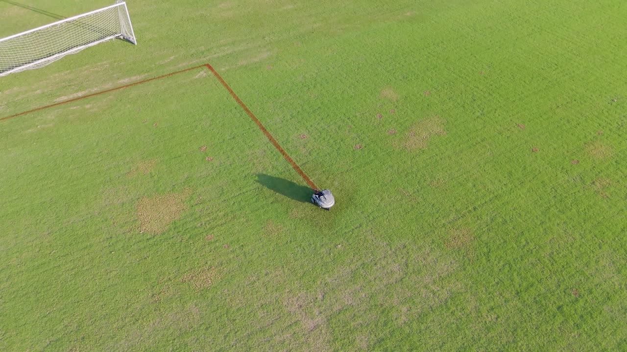 A robot autonomously paints precise lines on a soccer field under bright daylight, enhancing field markings efficiently