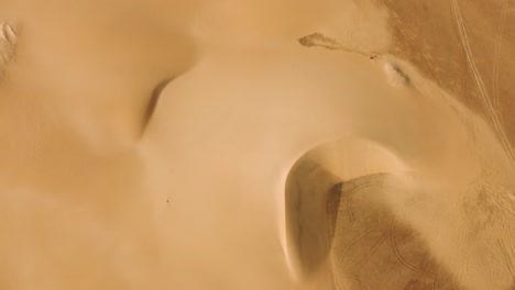 dunas de arena amarillas del desierto en la vista aérea de arriba hacia abajo inclinada hacia arriba