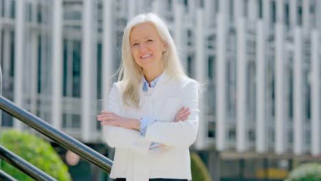 smiling senior businesswoman in white jacket standing outdoors