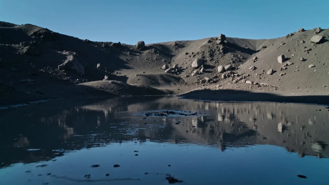 Piccola perturbazione che si forma al centro, causando un lago craterico che invia anelli sull'acqua a specchio nel bacino.