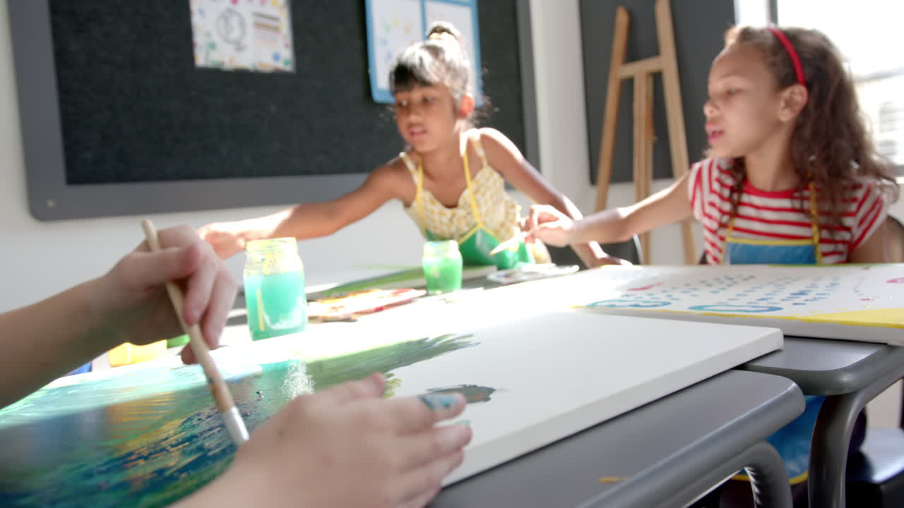 In school, two girls painting on canvases in art classroom, enjoying creativity