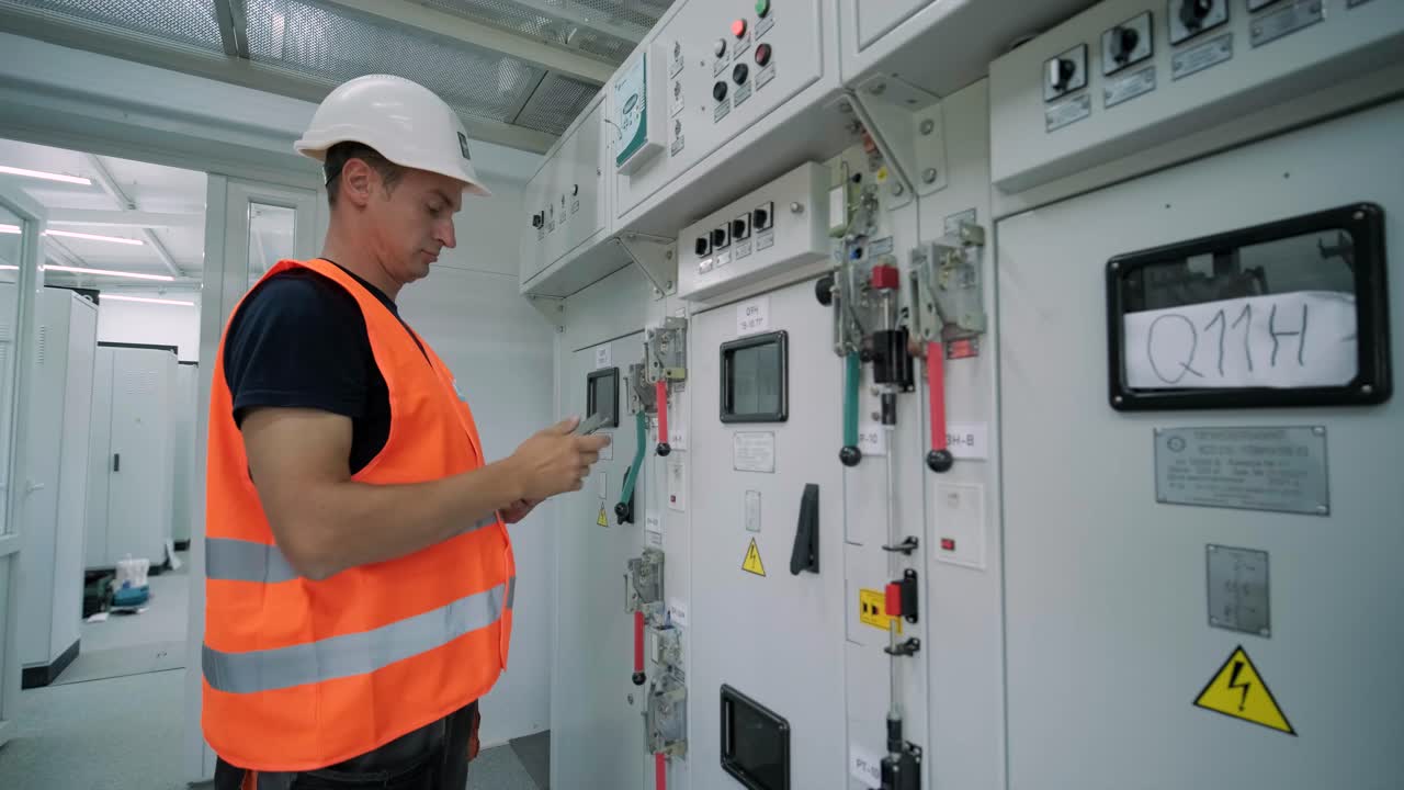 el ingeniero eléctrico que trabaja comprueba la tensión de corriente eléctrica y la sobrecarga en la parte delantera del gabinete del centro de carga o de la unidad de consumo para el mantenimiento en la sala principal del sistema de distribución de energía.