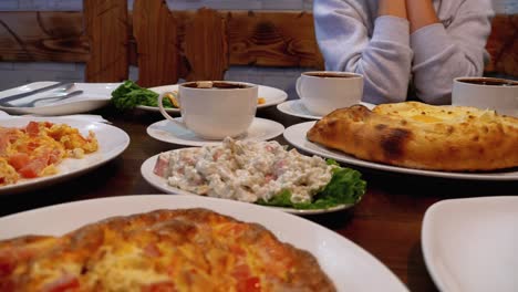 adjarian khachapuri on a table in a georgian restaurant next to salad, omelette and coffee