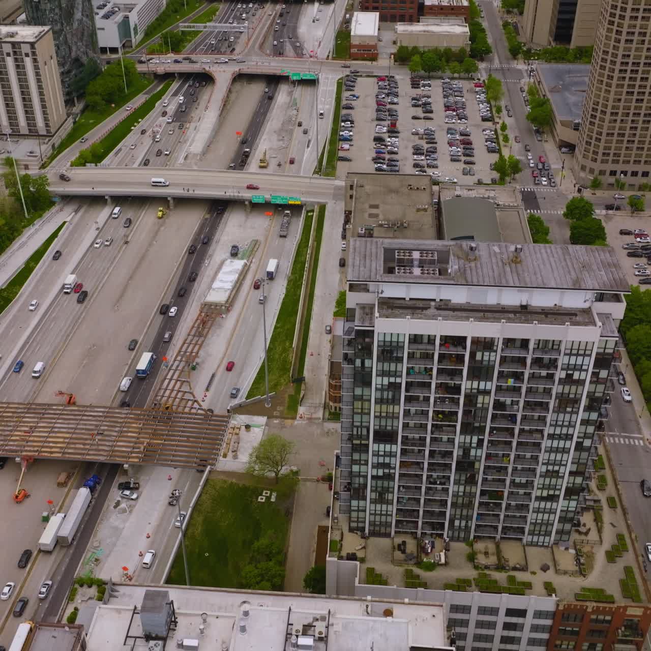 Multiple busy roads with lots of cars on crossing the downtown of contemporary Chicago. Huge parking lots full of cars nearby multi-storied buildings. Top view