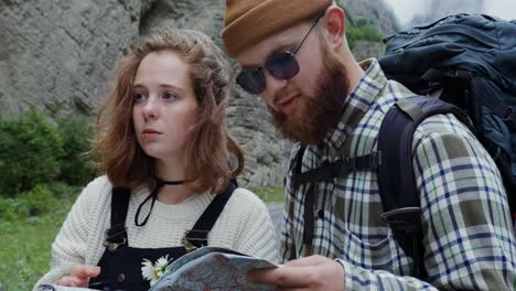 couple hiking and using map in mountains