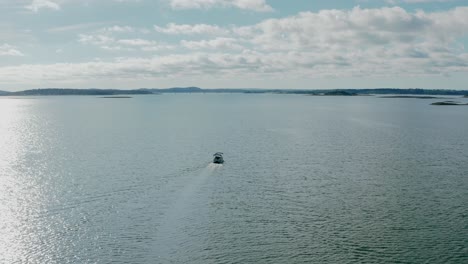 small-motorboat-sailing-in-calm-open-water-on-sunny-summer-day,-aerial-view