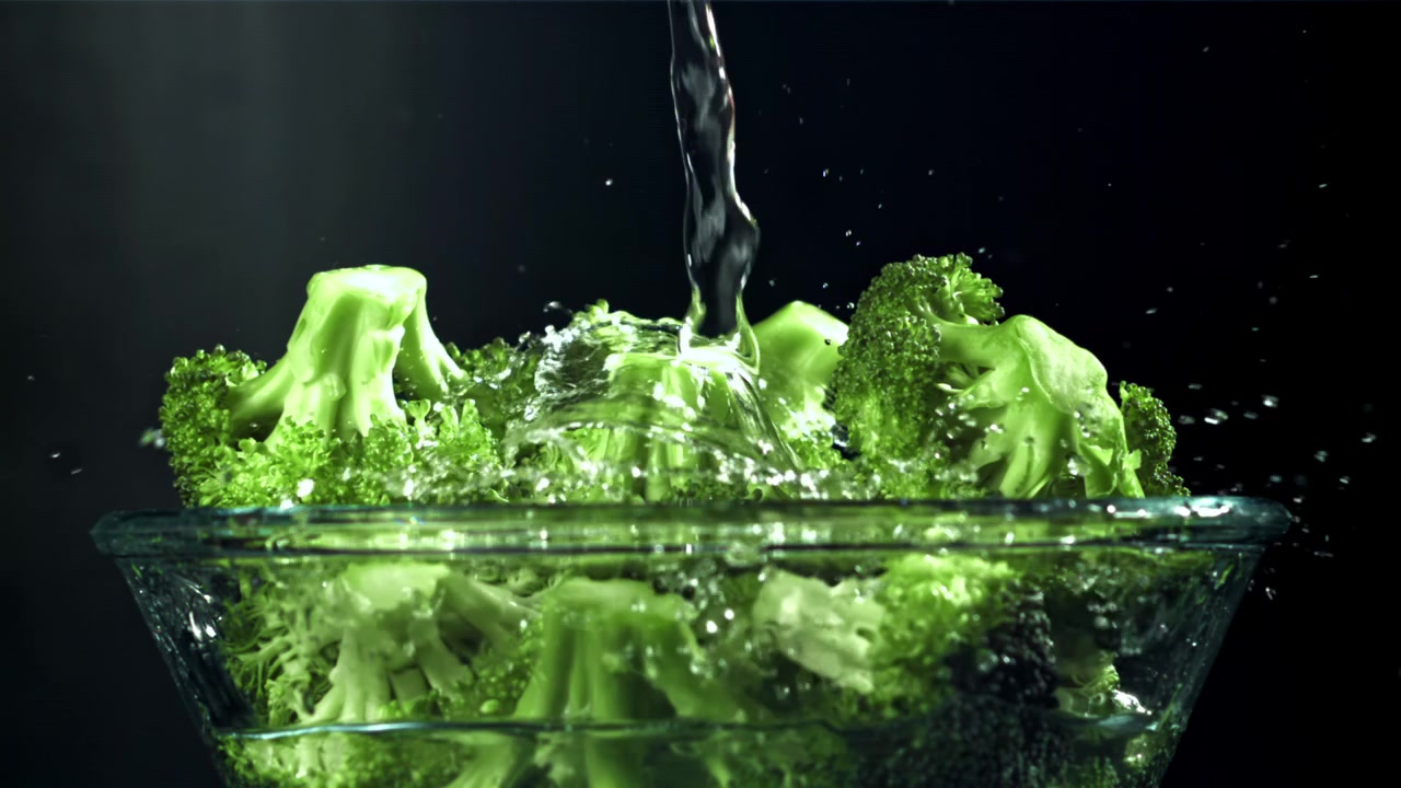 Lavaggio di broccoli verdi freschi con acqua in una ciotola di vetro
