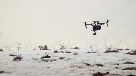 gran dron profesional dji inspire 2 con cámara de video vuela bajo sobre la nieve mientras sopla un fuerte viento-2