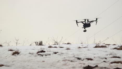 big professional drone dji inspire 2 with video camera flies low over the snow while blowing a strong wind-2