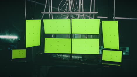 multiple green screen monitors in a dark room