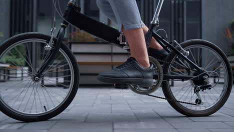 closeup worker legs pedaling at downtown district. eco-friendly transportation.