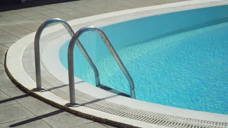 pasamanos de acero inoxidable en la piscina con agua turquesa en verano