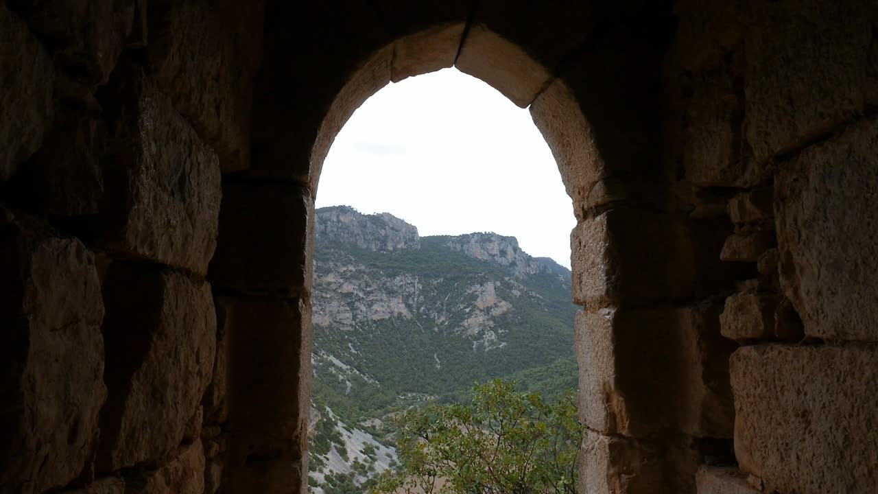 Stone arch and ruined walls of Otiñar Castle, Jaén, with a wide view of the hills and landscape