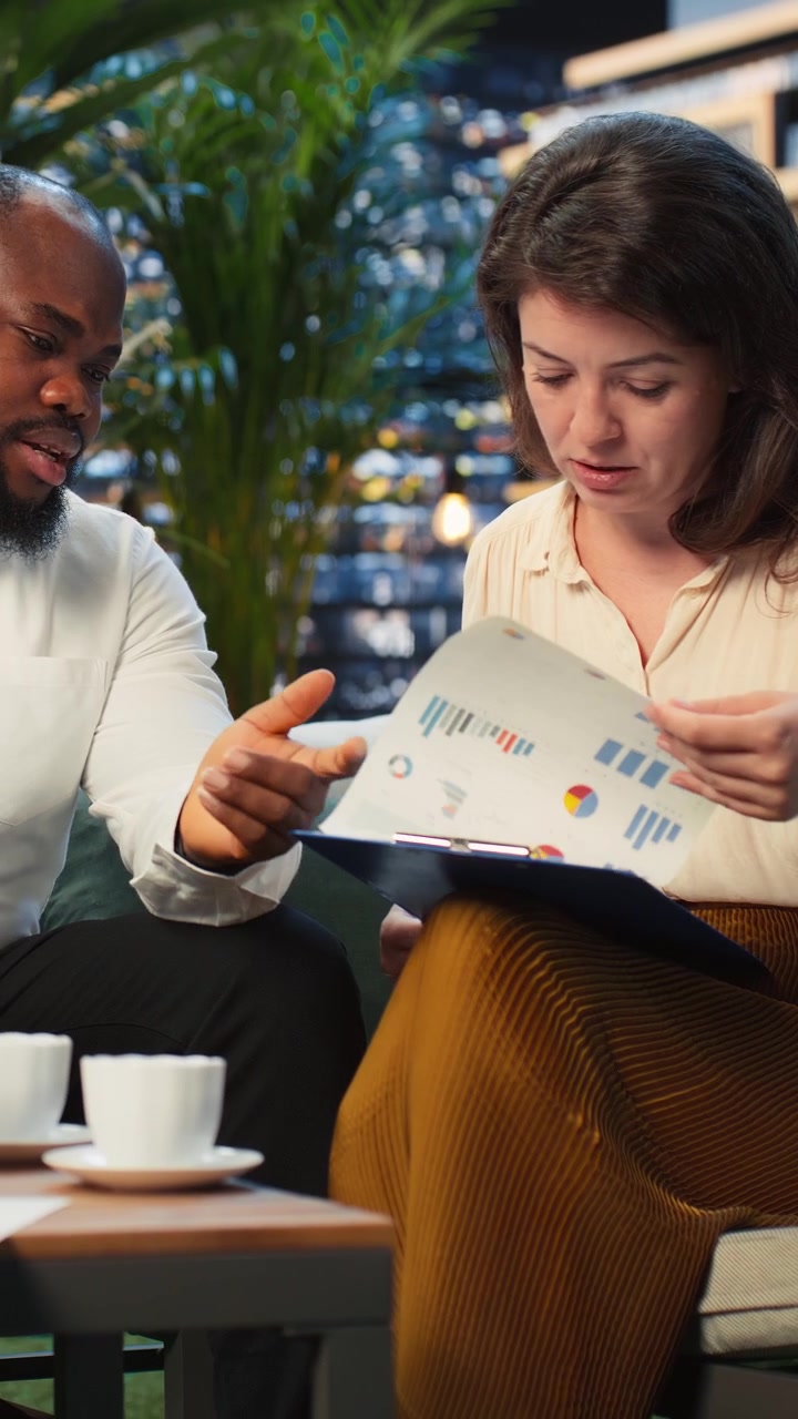 Vertical video Businessman leading discussion with coworkers on rooftop lounge