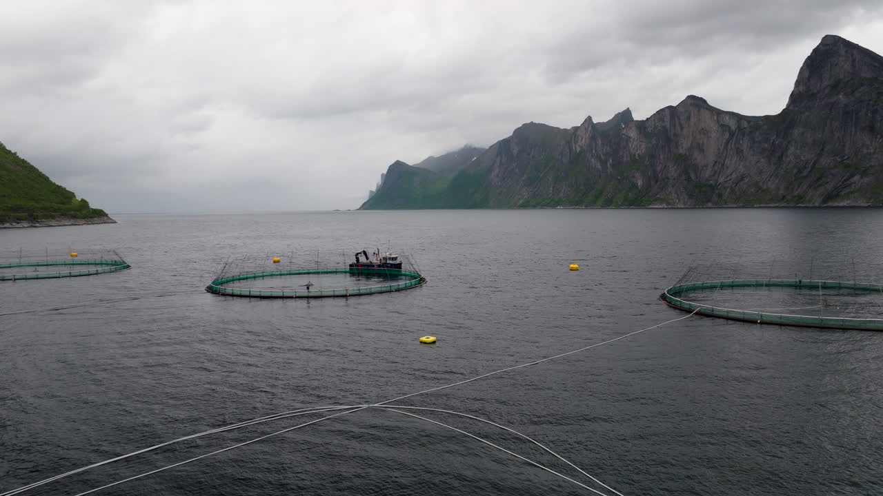 Aerial pullback view over Mefjord aquaculture salmon farm in Senja Norway