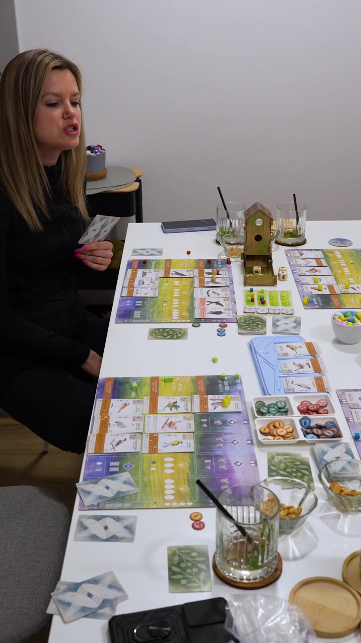 Vista verticale di una serata di giochi in famiglia che gioca al gioco da tavolo Wingspan a casa