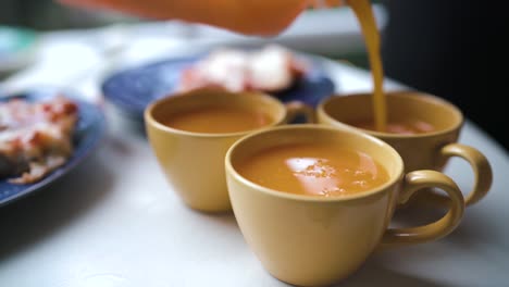 cerca de tres vasos amarillos que se llenan de jugo de naranja al aire libre