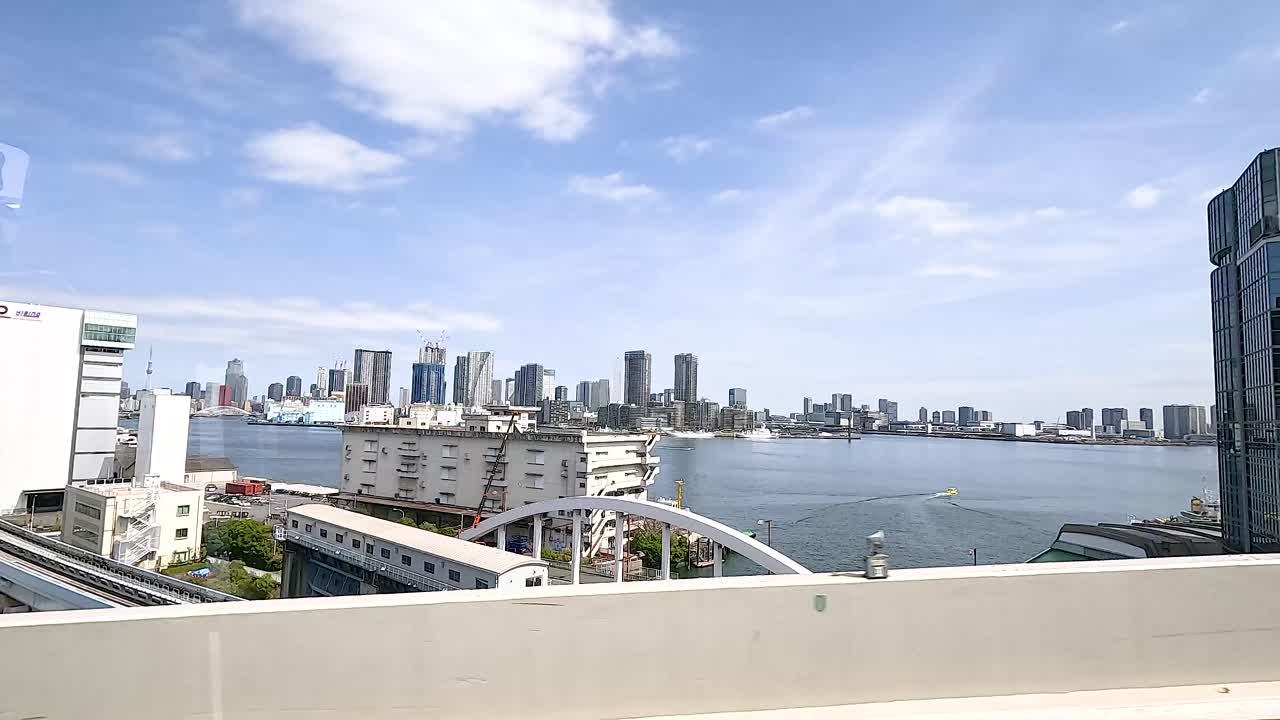 A dynamic view of Tokyo's skyline from a moving vehicle, showcasing modern architecture and a clear blue sky