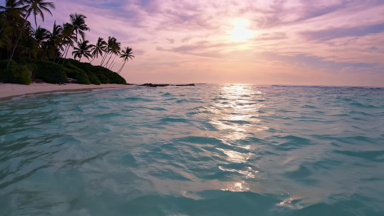 Tranquil turquoise ocean water reflecting a stunning purple sunset, with silhouettes of palm trees and lush vegetation on a tropical island beach in the background