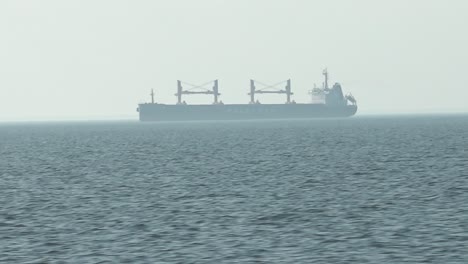 a cargo ship is sailing in a small mist on the sea horizon