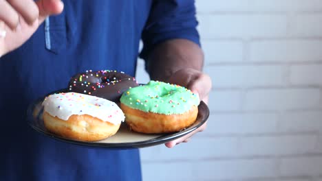 person holding a plate of assorted donuts