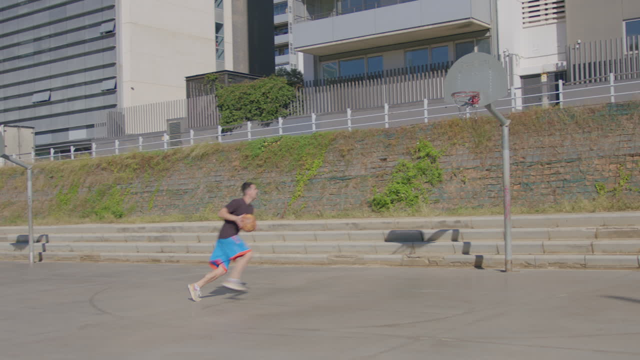 길거리 농구 코트에서 레이업을 하는 젊은 백인 남자의 일반적인 샷