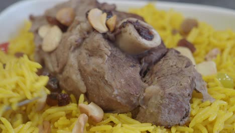 close up of a plate of yellow rice with lamb, almonds, and raisins