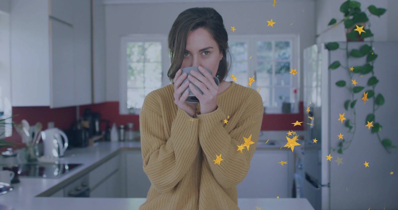Donna con una tazza in cucina che la alza per sorseggiare, mentre stelle gialle fluttuano a destra passando davanti a casa.