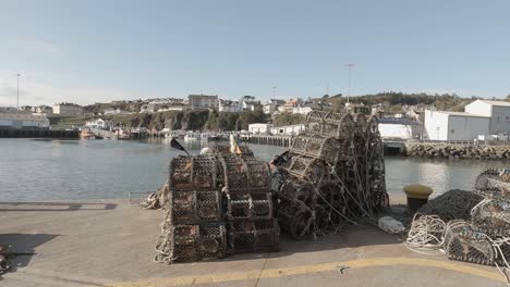 lobster pots stacked on pier await fishermen on sunny seaside day