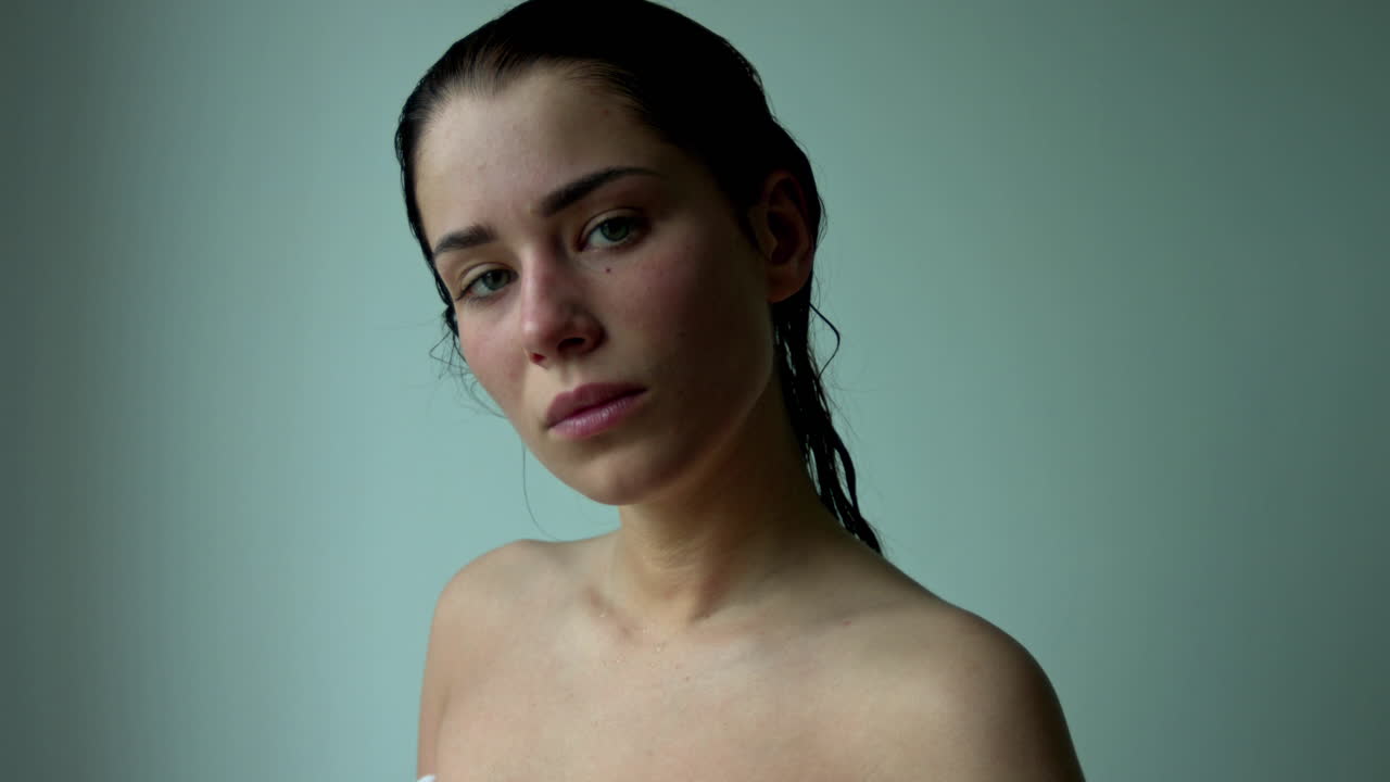 Wet woman headshot. Beautiful woman is standing and looking at camera, after shower. She is got wet hair, face and shoulders