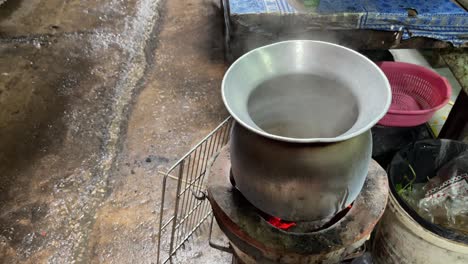 hot boiling steam comes off from a pot on the thai charcoal stove