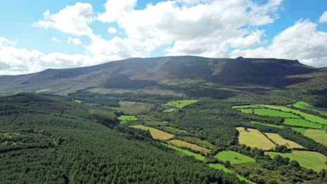 Montañas-Comeragh-Waterford-Irlanda-Drone-Estableciendo-Un-Disparo-Volando-Sobre-Bosques-Y-Tierras-De-Cultivo-En-Una-Tarde-De-Verano