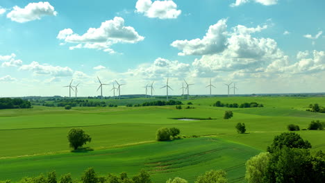 expansive green farmland with wind turbines in the distance and a partly cloudy sky