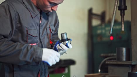 factory worker measuring detail. man measuring part with callipers in workshop
