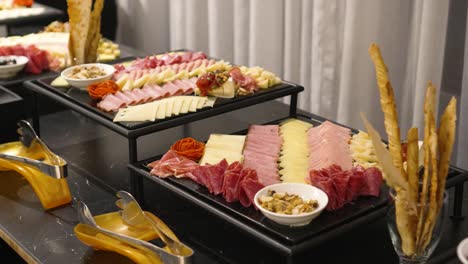 mesa de buffet con quesos, tocino y jamones, durante el banquete en la sala de celebración de la boda