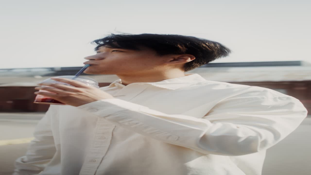 밖에서 음료를 마시는 젊은 남자