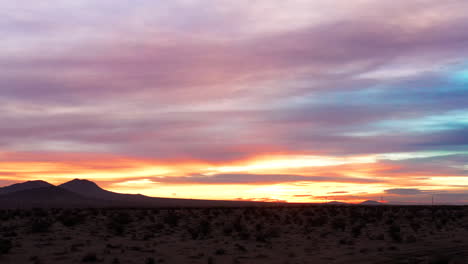 an amazingly colorful sky over the mojave desert as the setting or rising sun illuminates the clouds - sliding wide angle view