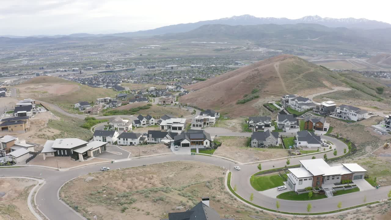 tomada aérea de grandes casas de lujo en la ladera de traverse mountain, lehi utah en un día nublado, tiro atrás