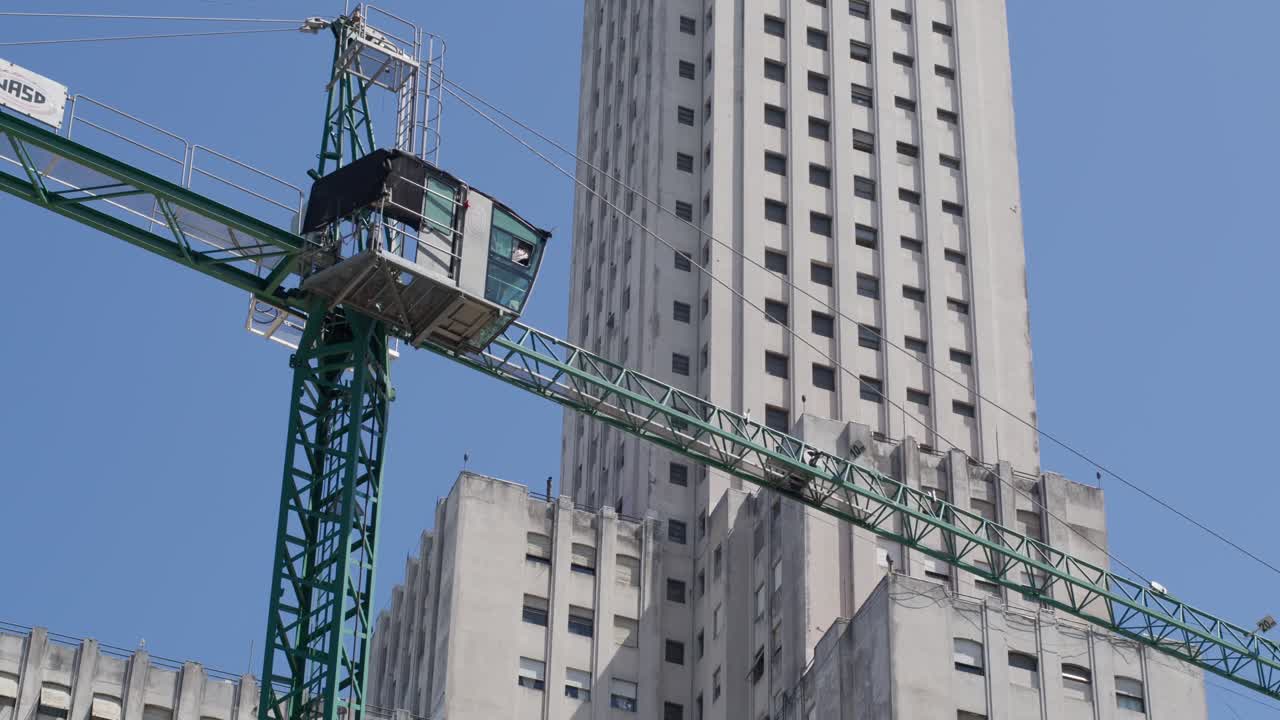 A construction crane lifting materials on a building site in Argentina, depicting urban growth
