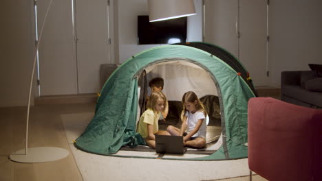 kids watching movie on laptop in tent