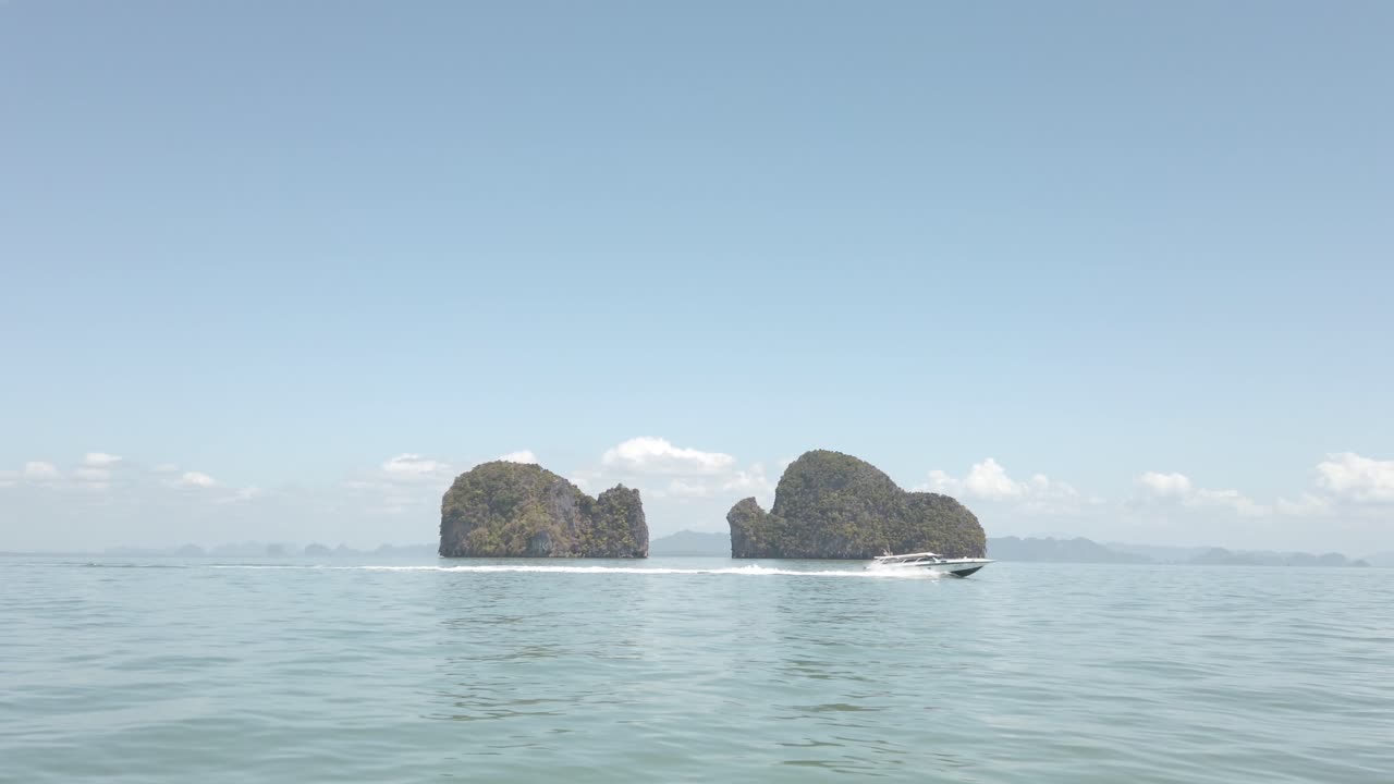 A speedboat drives by an island that looks like a small elephant, Phuket Thailand.