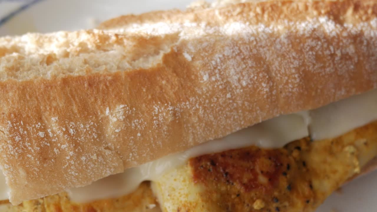 Close-up of a chicken bocadillo sandwich with melted cheese on crispy bread