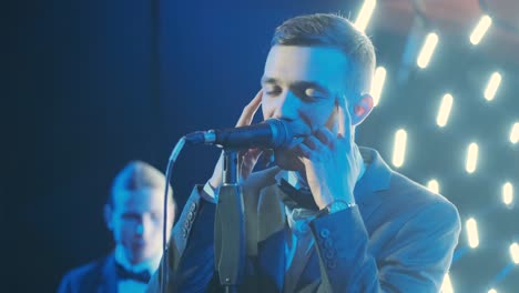 man singing song in microphone during performance on stage on rock concert. close up man rock star singer on music concert on colorful light background