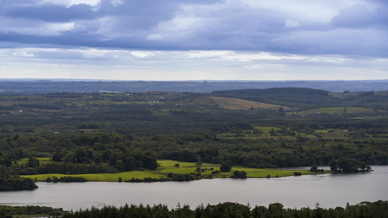 Time lapse of rural farming landscape with lake, forest and hills during a cloudy day viewed from above Lough Meelagh in county Roscommon in Ireland