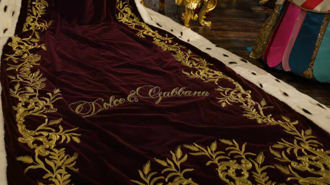 Close up detail of gold embroidery name Dolce and Gabbana on royal red robe