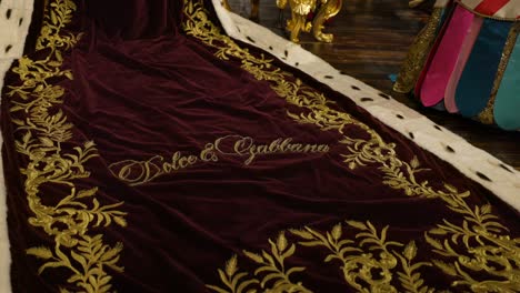 close up detail of gold embroidery name dolce and gabbana on royal red robe