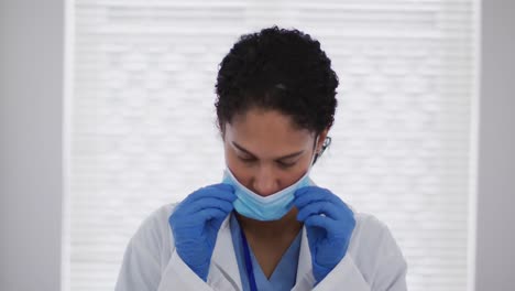 Portrait-of-mixed-race-female-doctor-putting-a-face-mask-on