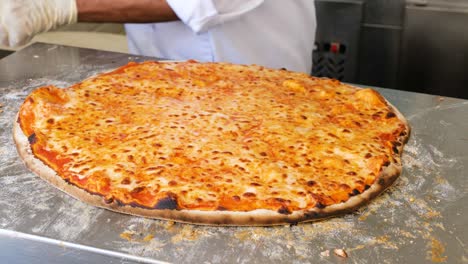 chef cutting pizza with a round cutter knife