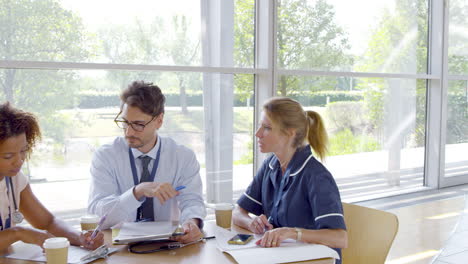 medical team having meeting sitting around table in hospital